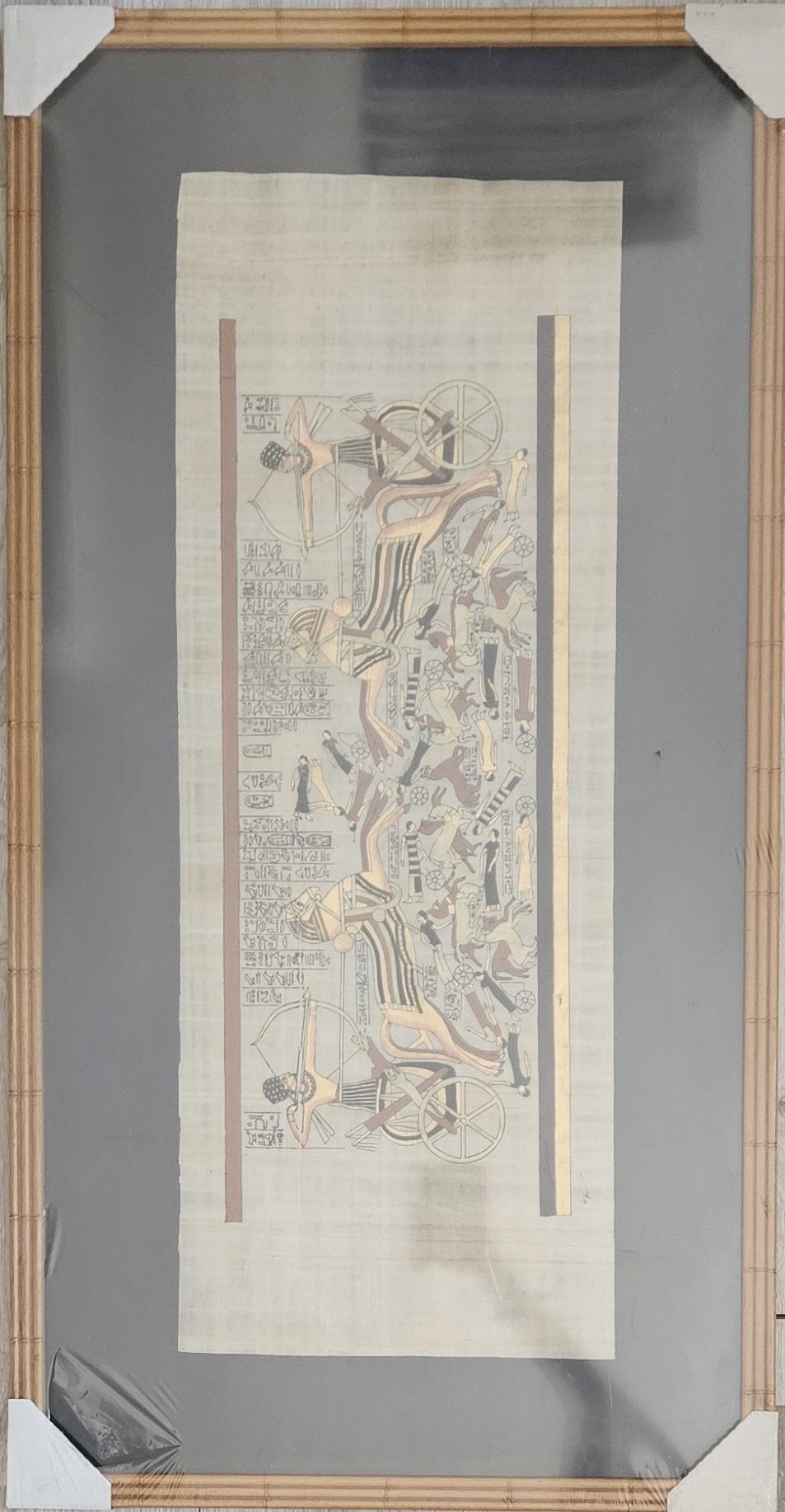 Obraz Egyptský motív: Bojové vozy a hieroglyfy na plátne s výzorom papyrusu v bambusovom ráme 54,5 x 108 cm